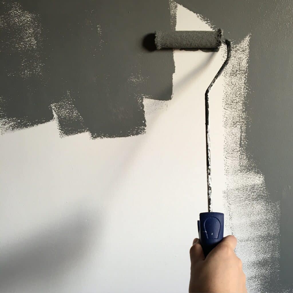 person holding paint roller while painting the wall 994164
